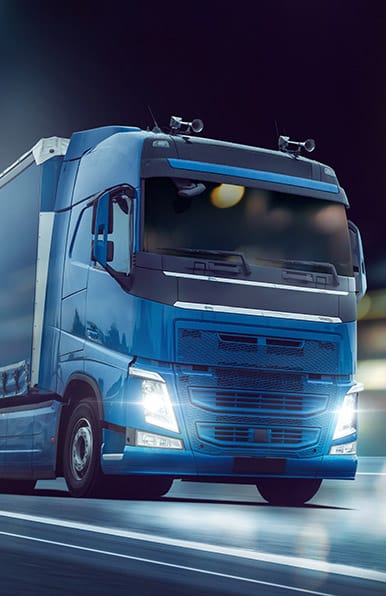 Routier Volvo Bleu Vif de Nuit, Transport Express Tracteur Volvo bleu vif circulant rapidement sur autoroute la nuit, phares allumés, lumières de toit visibles.